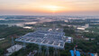 © tai - This aerial shot shows a large high voltage power substation at dawn, surrounded by rural wetlands and woodlands under a sunrise sky.