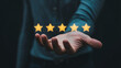 © Bina digital - Hand holding five stars icon representing high quality rating customer experience or excellent feedback service evaluation.