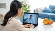 © suryono - Woman having a video call with her doctor at home.