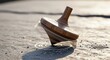 © Mangdin - A classic wooden spinning top toy rotating on a textured stone surface with warm sunlight and depth of field