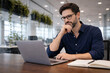 © hr-gold - Focused businessman working on laptop in a modern office setting