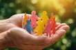 © Viktoryia - hands holding circle of diverse colorful paper people cutouts outdoors against sunny green nature background for environmental protection eco community global harmony and unity