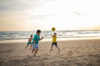 © KONSTANTIN SHISHKIN - Three boys playing beach soccer on sandy shore