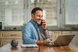 © Miljan Živković - Smiling man working from home talking on phone