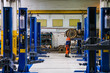 © SGr - Blue-colored car lifts located in a row in an auto repair shop or garage with several car service stations.