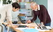 © JackF - Drawing is laid out on table, male engineers review and evaluate project work, consult and plan changes and adjustments to master plan.