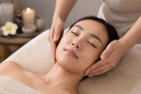 Young Asian woman receiving relaxing facial massage in spa salon with soft candlelight ambiance, tranquil wellness and beauty treatment concept, gentle hands skincare therapy
