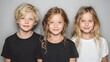© sirisak - Three cute children stand side by side, one boy with blond hair and two blonde girls smiling against a simple light gray backdrop portrait.