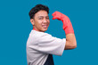 © Gatot - Cheerful Young Asian Man in an apron and Red Rubber Gloves Showing His Biceps