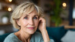 © v.stock - Portrait elegant senior woman in a cozy psychological therapy room, sitting and looking at the camera while gently touching her short blonde hair, mental health support and wellness concept.