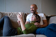 © Westend61 - Smiling couple taking a selfie together on sofa indoors