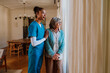 © Westend61 - Caregiver in blue scrubs supporting senior woman at home