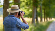 © Nataliya - Rear view of a senior man photographing nature in a park with a camera, outdoor photography hobby concept, retirement creative lifestyle, nature exploration, defocused background, with copy