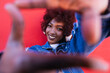 © VISTA by Westend61 - Smiling woman with afro making finger frame against red wall