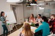 © deagreez - Business team meeting with a young woman presenting ideas on a flip chart during a collaborative office brainstorming session