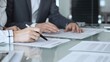 © rogerphoto - Group of professional business people sitting at a meeting table, reading and discussing contract terms, financial agreements. Collaboration, teamwork, and corporate communication concept