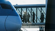 © HABI ANGGARA PUTRA - Silhouette of passengers walking through a glass jet bridge to board a large modern airplane at the airport