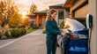 © Argiduna - Person plugging in electric car at home at sunset, warm cinematic light, subtle smile, clean driveway, minimal distractions, ad-ready composition.