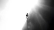 © Rikza - Dramatic silhouette of rock climber ascending vertical cliff in sun.