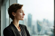 © wolfhound911 - Confident businesswoman standing near office window looking forward, city skyline softly blurred in background, natural daylight illumination, professional corporate lifestyle scene, visual for social