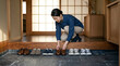 © Sanjay Design - Japanese Woman Kneeling to Organize Shoes at Entrance of Traditional Home