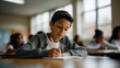 © Favio - Hispanic school boy student writing in notebook in classroom focused learning education environment young male pupil studying.