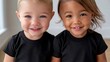 © www.freund-foto.de - Zwei lächelnde Kleinkinder – ein helles und ein dunkelhäutiges – in schwarzen T-Shirts vor weißem Hintergrund