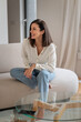 © gzorgz - Attractive brunette haired woman relaxing on a couch in her minimalist living room
