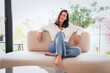 © gzorgz - Attractive brunette haired woman relaxing on a couch in her minimalist living room