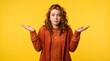 © W.O.W - Redhead woman shrugging with confused expression. Young girl gesturing uncertainty or doubt on yellow background. Casual portrait expressing bewilderment and ignorance about something.