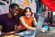 © Marko Geber - Young adults collaborating on laptop at outdoor cafe