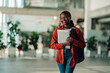 © Zamrznuti tonovi - African american female student confidently walking on university campus, carrying a laptop and backpack