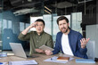 © Liubomir - Diverse business partners sitting at an office desk, looking shocked and frustrated at the camera while experiencing confusion and stress about a mistake or problem