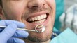 © Creatify_Tech - Close up of man smiling during dental check up, dentist examining teeth with small mirror.