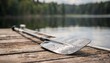 © Justlight - Closeup of a kayak paddle resting on a rental dock with a blurred lake and forest backdrop highlighting easy access to outdoor watercraft gear.
