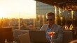 © kwanchaift - Man enjoying sunset on rooftop terrace with cocktail and laptop, modern city skyline view, relaxed atmosphere, stylish attire and sunglasses