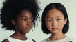 © Babb - Two young girls standing together on plain backdrop