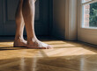 © RUTTAMPUBOLON - Barefoot steps on warm wooden floors bathed in natural light from a sunlit window, creating a serene morning atmosphere