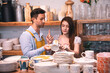 © chokniti - Pottery shop assistant and customer select ceramic mug in craft store interior