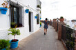 © Cavan Images - Woman walking along white village street with flower pots