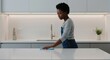 © NN AI - Young Black woman cleaning modern kitchen countertop with cloth. Domestic housekeeping chores and home hygiene concept