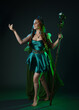 © faestock - Full length portrait of female model wearing fantasy fairy costume, green dress, cloak, butterfly wings and crown. Full length walking pose holding druid staff.  isolated on dark studio background.