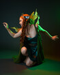 © faestock - portrait of female model wearing fantasy fairy costume, green dress, cloak, butterfly wings and crown. full length sitting pose, kneeling on floor, dark studio background.