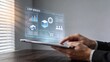© Sophia - Businessman holding tablet with holographic ERP management planning interface futuristic office technology dashboard data analytics bar charts gear settings warehouse storage