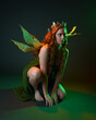 © faestock - portrait of female model wearing fantasy fairy costume, green dress, cloak, butterfly wings and crown. full length sitting pose, kneeling on floor, dark studio background.