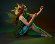 © faestock - portrait of female model wearing fantasy fairy costume, green dress, cloak, butterfly wings and crown. full length sitting pose, kneeling on floor, dark studio background.