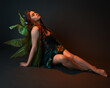 © faestock - portrait of female model wearing fantasy fairy costume, green dress, cloak, butterfly wings and crown. full length sitting pose, kneeling on floor, dark studio background.