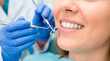© NikProArt - A close-up of a woman's bright white smile during a routine dental examination with a dentist's instruments