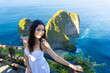 © DR26 - Young woman in white dress posing at Kelingking Beach on Nusa Penida, Bali, with iconic cliffs and ocean backdrop.