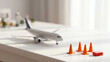 © M_Texture_Works JP - 白いテーブルの上に置かれたミニチュアの飛行機とカラーコーン、救急箱